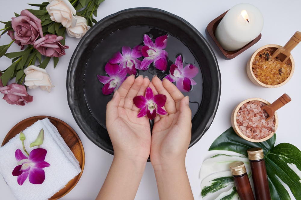 Woman Soaking Her Hands in Bowl of Water With Petals